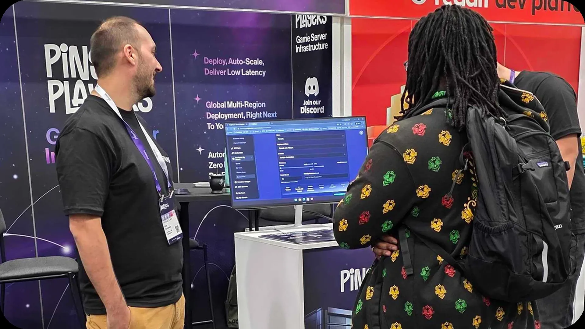 Un miembro del equipo de PingPlayers mostrando el panel de control a un visitante en el stand de GDC