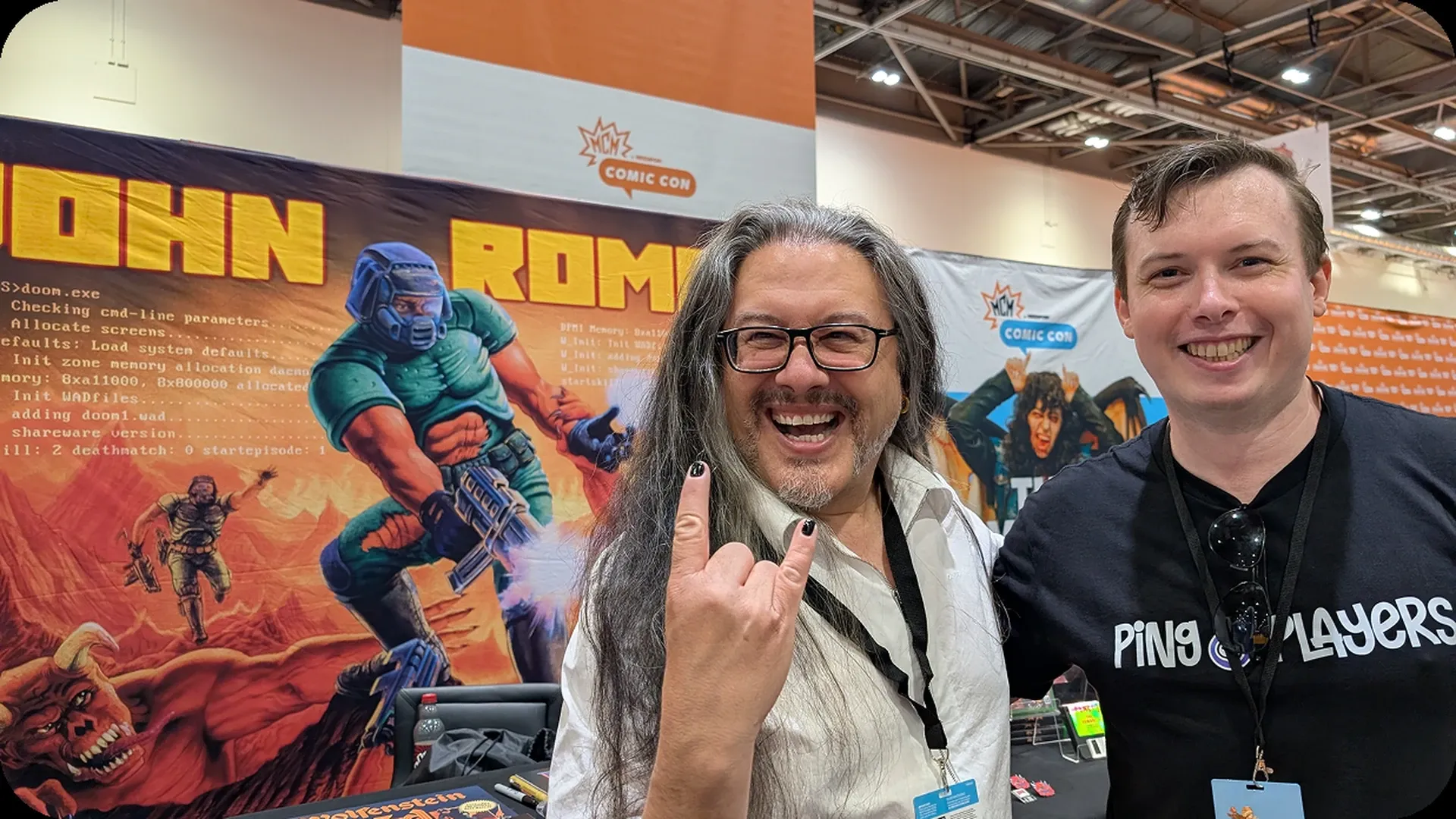 Un miembro del equipo de PingPlayers con John Romero en una convención