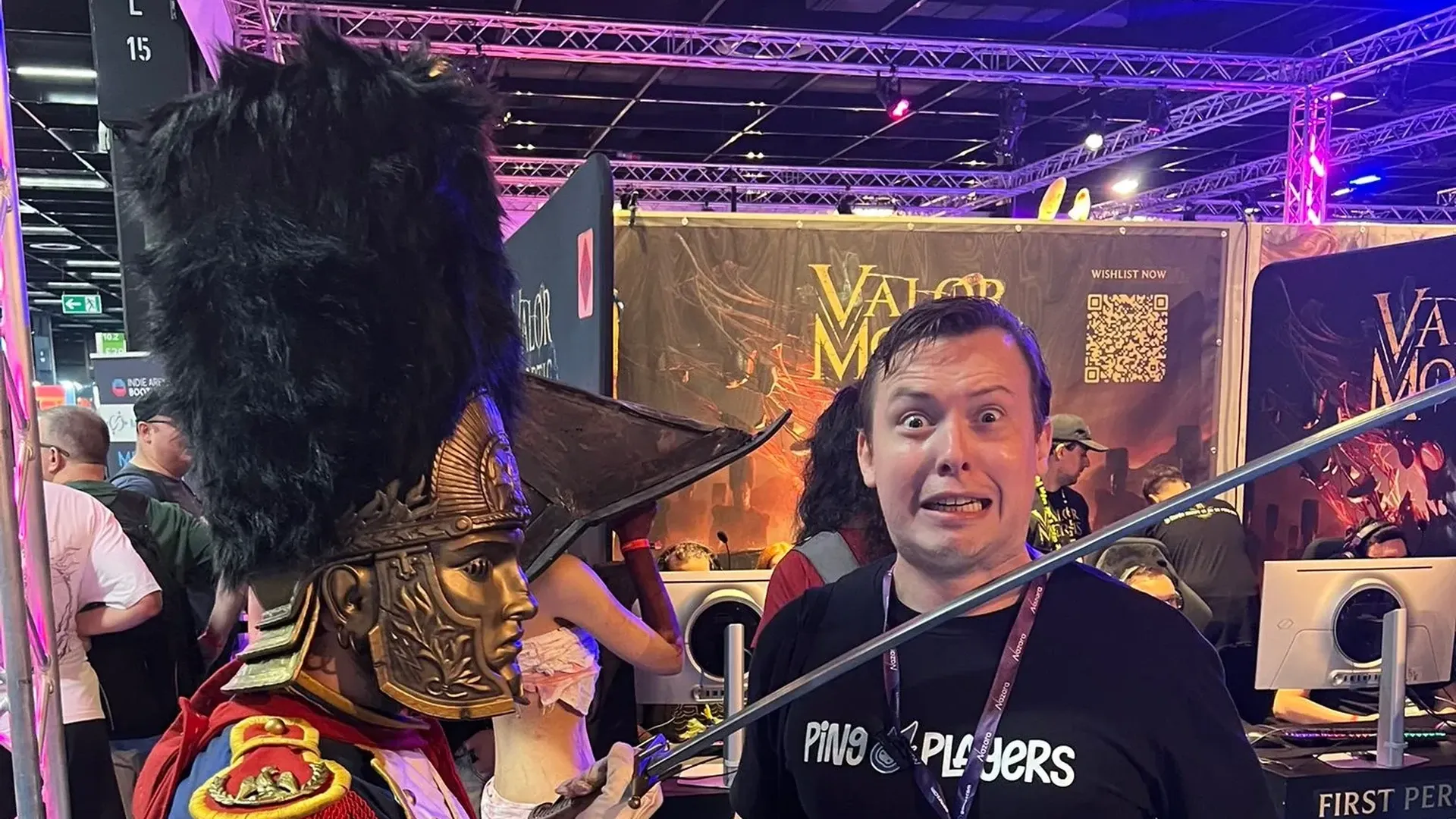 Un cosplayer con armadura hecha a mano apuntando con una espada a un miembro del equipo de PingPlayers en Gamescom 2026