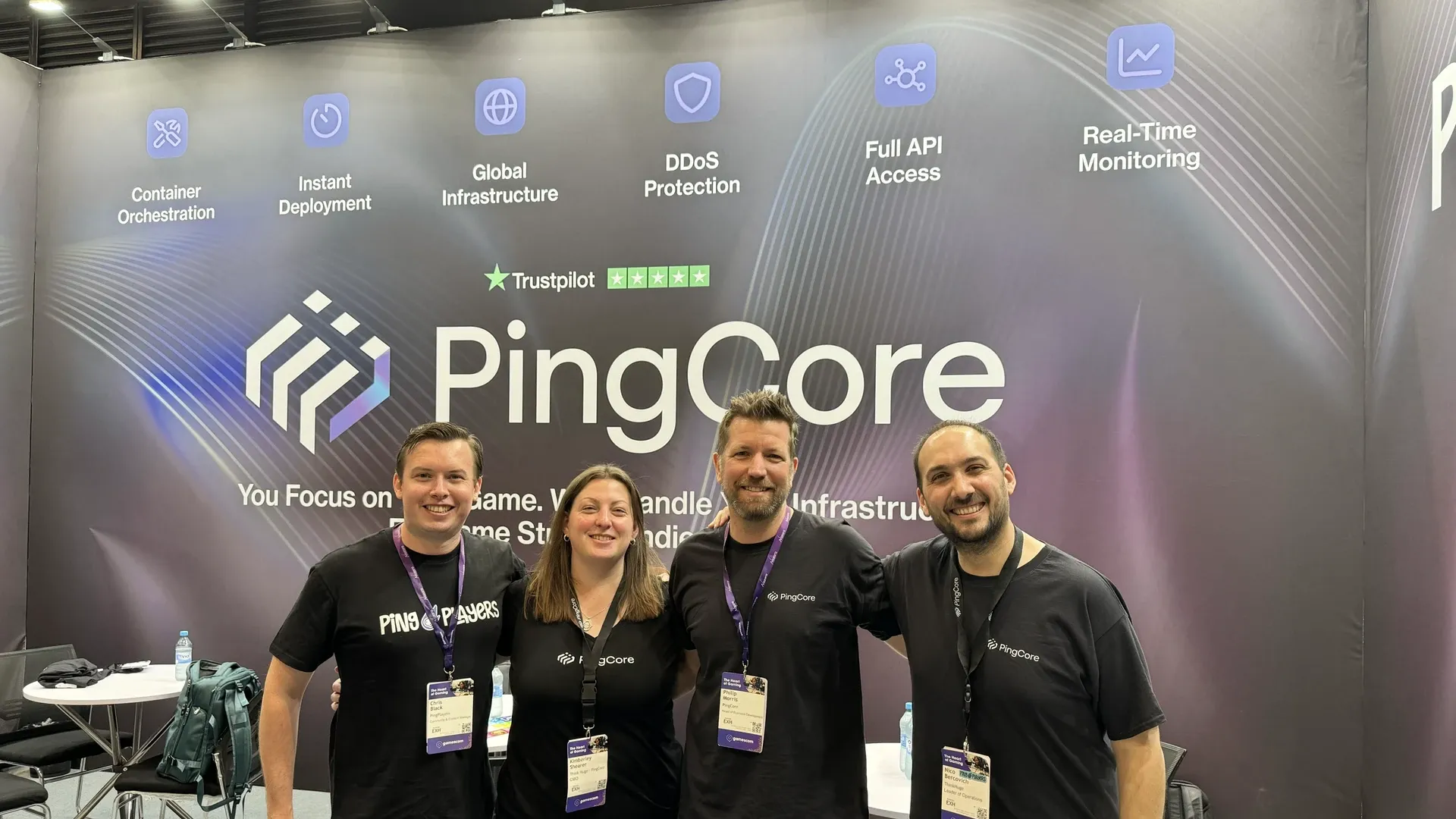 Cuatro miembros del equipo de PingPlayers y PingCore frente al banner del stand en Gamescom 2026