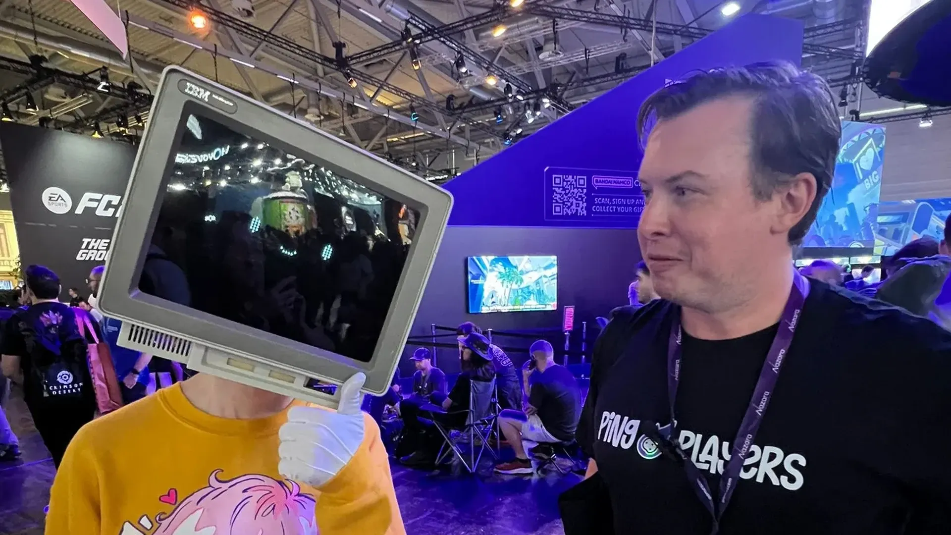 Un miembro del equipo de PingPlayers hablando con un cosplayer que lleva un disfraz de monitor CRT en la feria de Gamescom